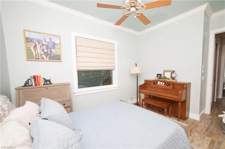 Bedroom with baseboards, a ceiling fan, wood finished floors, and crown molding
