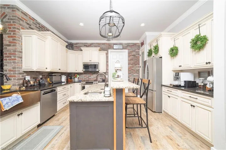 Kitchen with a sink, light wood-style floors, a center island with sink, a kitchen bar, and appliances with stainless steel finishes