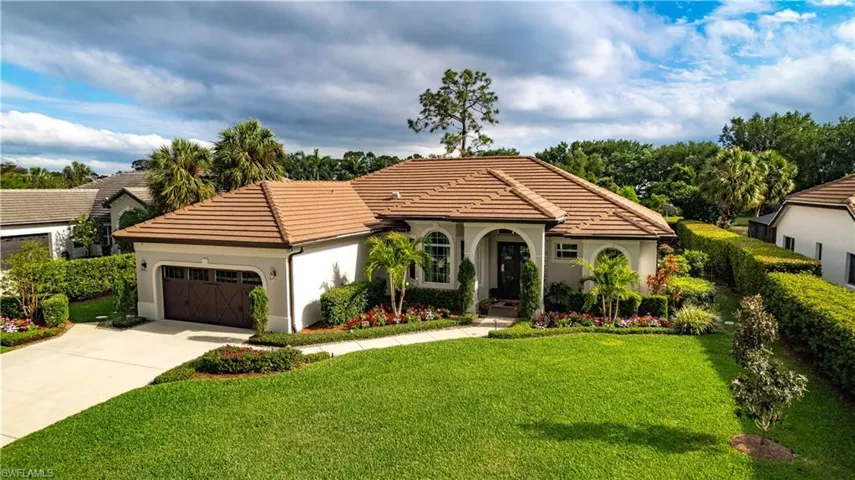 Mediterranean / spanish-style house featuring stucco siding, a tile roof, driveway, a front yard, and a garage