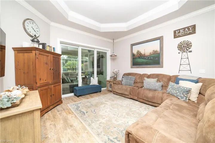 Living room with a tray ceiling, light wood-style floors, and crown molding