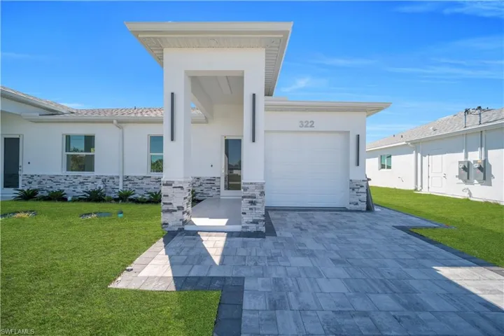View of front of property featuring a front lawn, an attached garage, stucco siding, and stone siding