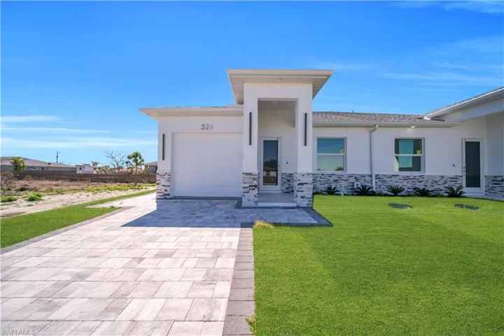 View of front of home featuring stone siding, a garage, a front yard, stucco siding, and driveway