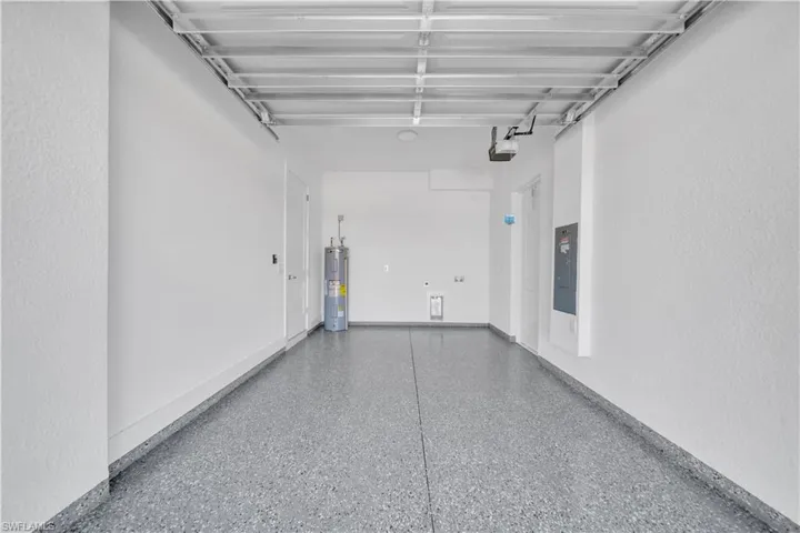 Garage featuring electric panel, electric water heater, and a textured wall