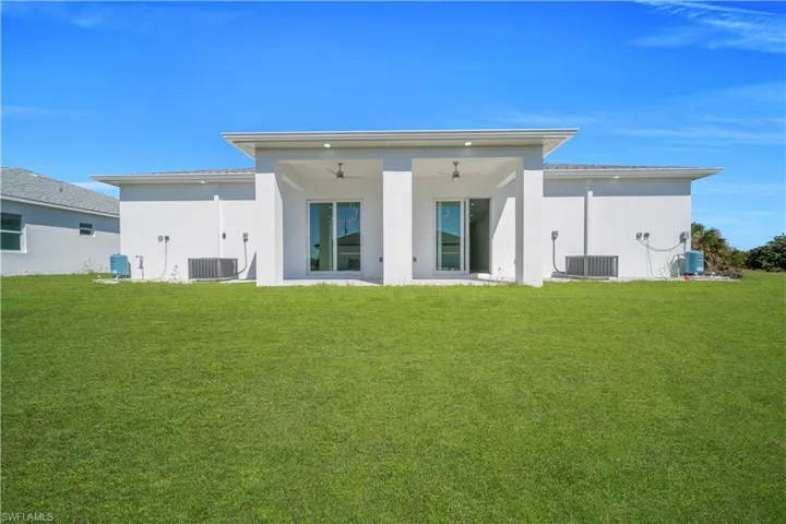 Rear view of property with a lawn, a patio, stucco siding, and a ceiling fan