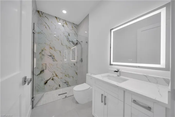 Bathroom featuring vanity, a marble finish shower, and recessed lighting