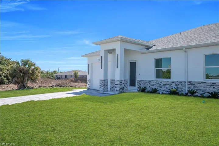 View of front of home featuring stone siding, a front yard, stucco siding, and an attached garage