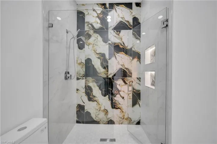 Full bathroom featuring a marble finish shower and toilet