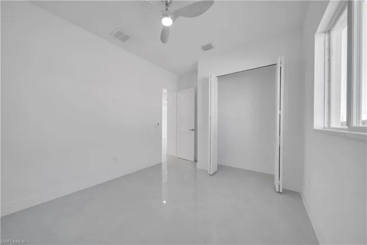 Unfurnished bedroom featuring concrete flooring, ceiling fan, and a closet