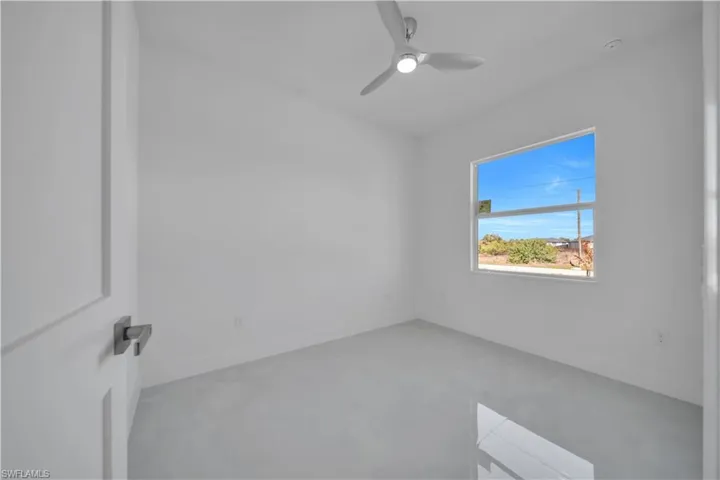 Unfurnished room featuring finished concrete flooring and ceiling fan