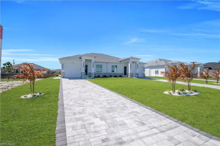 Prairie-style home featuring a front yard, stone siding, a garage, driveway, and stucco siding