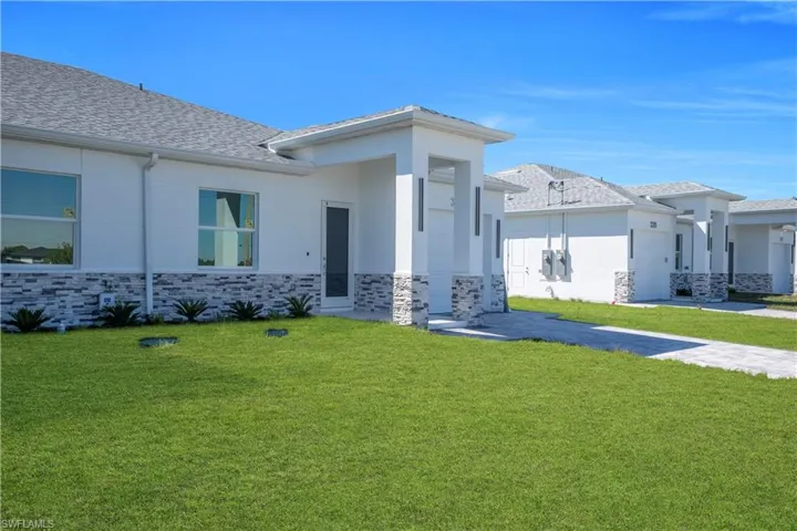 Prairie-style home with a front lawn, stone siding, and stucco siding