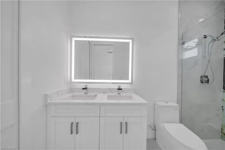 Bathroom featuring double vanity and a marble finish shower