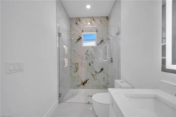 Full bath featuring a marble finish shower and vanity