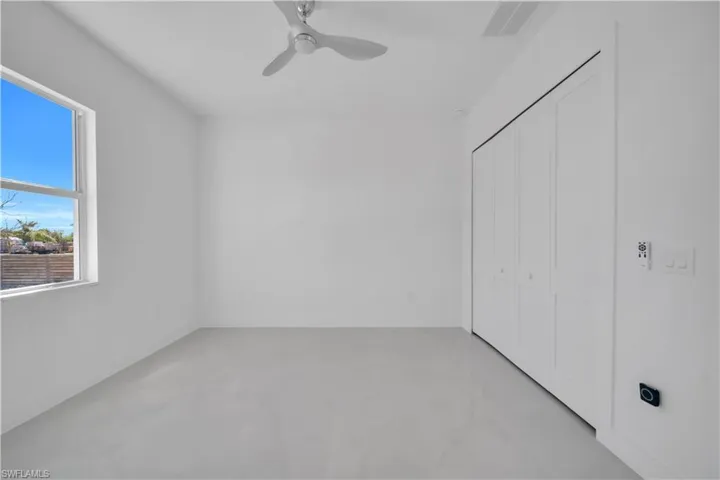 Unfurnished bedroom featuring concrete floors, ceiling fan, and a closet