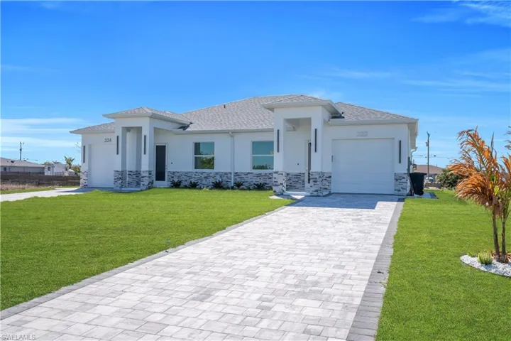 Prairie-style house with stone siding, an attached garage, decorative driveway, and a front yard