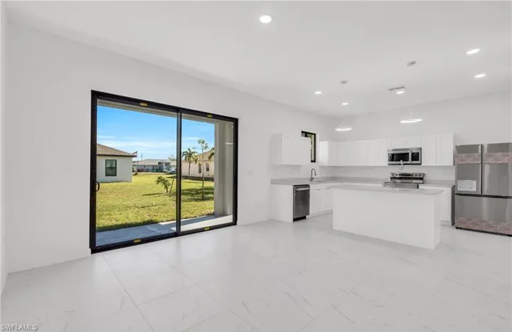 Kitchen featuring stainless steel appliances, light countertops, a kitchen island, and white cabinetry