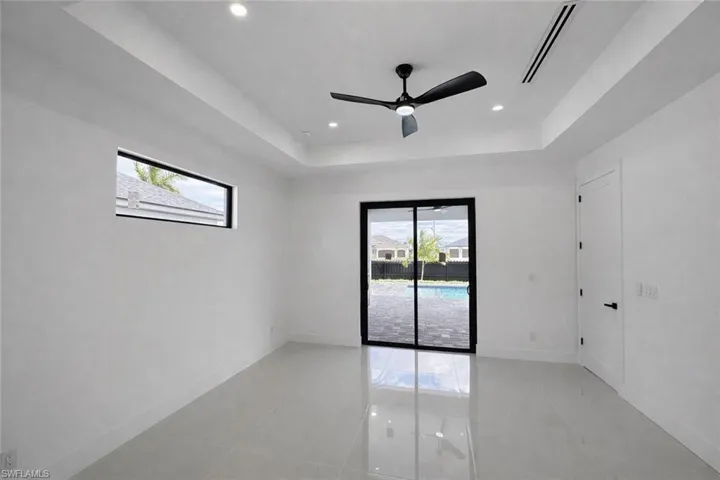 Spare room with healthy amount of natural light, ceiling fan, a tray ceiling, light tile patterned flooring, and recessed lighting