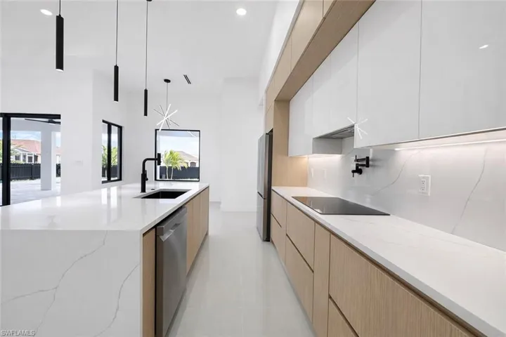Kitchen with two tone cabinetry, modern cabinets, light stone counters, a large island, and stainless steel appliances