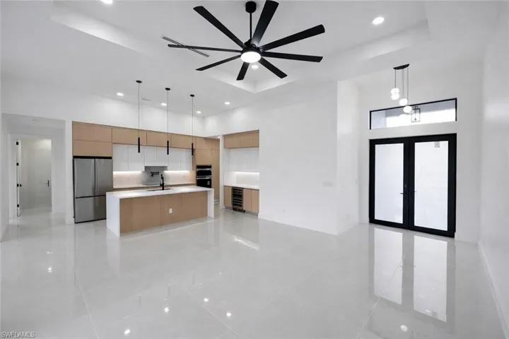 Kitchen with a spacious island, decorative light fixtures, a tray ceiling, freestanding refrigerator, and wine cooler