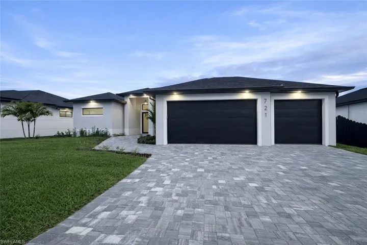 Prairie-style home featuring decorative driveway, a garage, and stucco siding