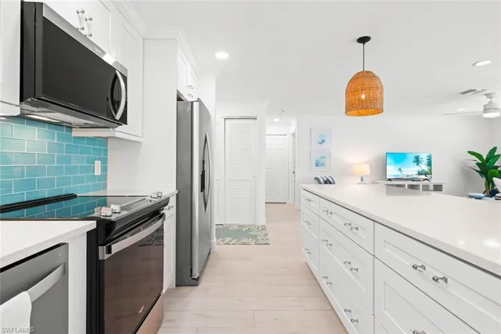 Kitchen featuring light countertops, tasteful backsplash, visible vents, white cabinets, and appliances with stainless steel finishes