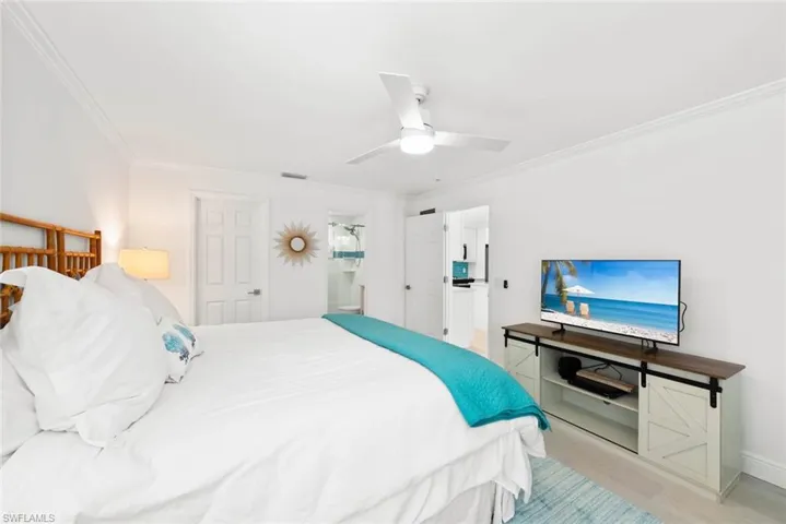 Bedroom with crown molding, light wood-style flooring, baseboards, visible vents, and ceiling fan