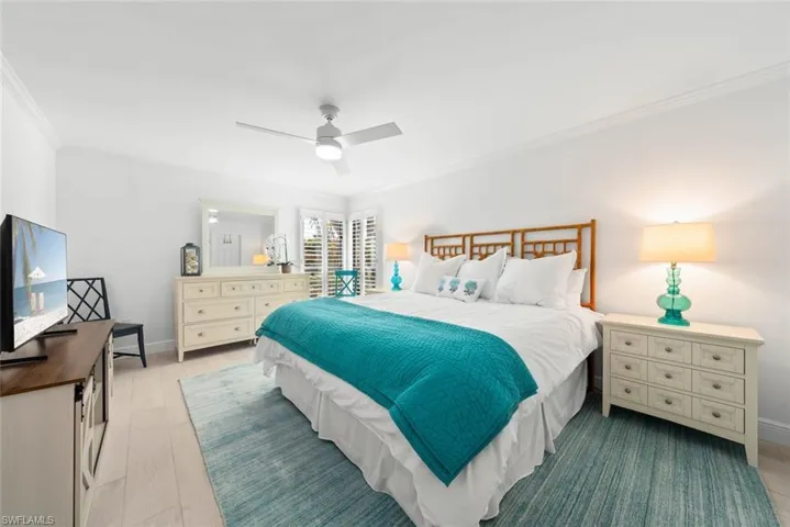 Bedroom featuring baseboards, wood finished floors, ceiling fan, and ornamental molding