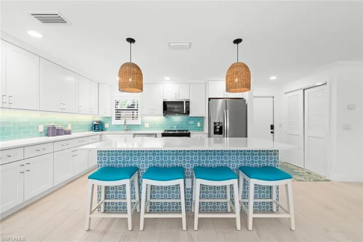 Kitchen featuring visible vents, a breakfast bar area, white cabinetry, and stainless steel appliances
