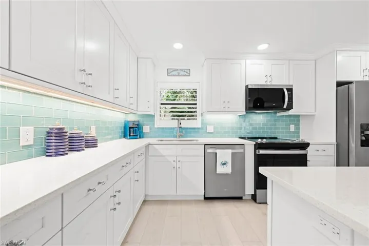 Kitchen featuring tasteful backsplash, recessed lighting, a sink, white cabinets, and appliances with stainless steel finishes