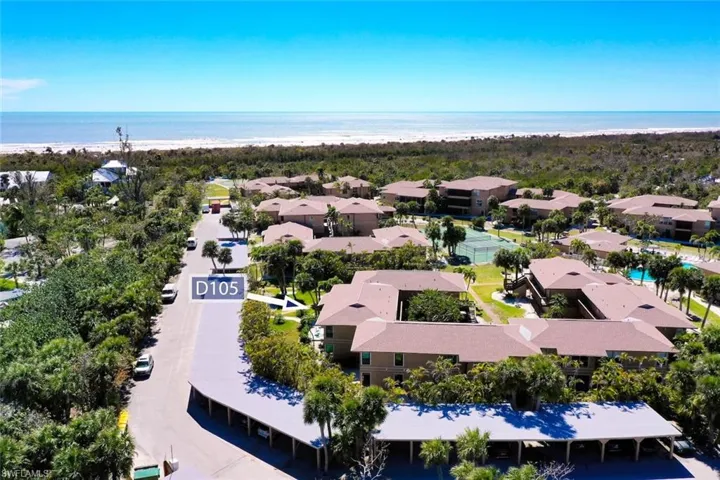 Birds eye view of property with a water view and a beach view