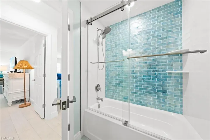 Bathroom with ornamental molding, shower / bath combination with glass door, and tile patterned flooring