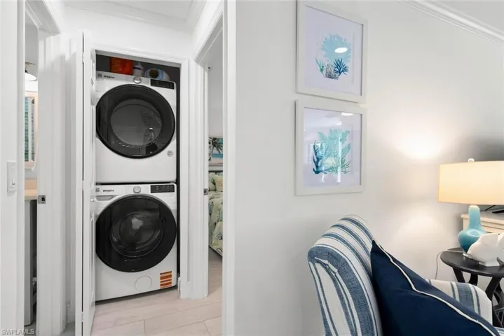 Laundry room with stacked washer and clothes dryer, laundry area, and crown molding