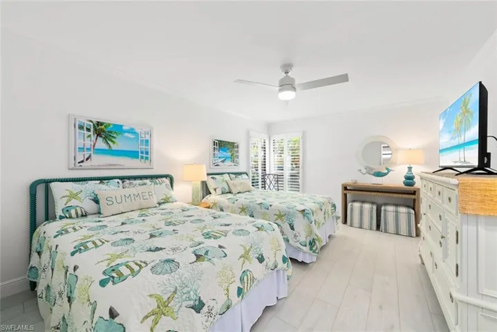 Bedroom featuring light wood-type flooring, ornamental molding, and a ceiling fan