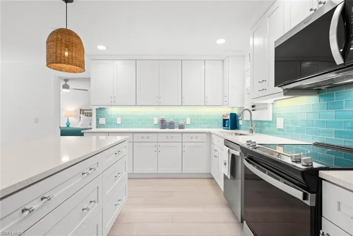 Kitchen with white cabinets, light countertops, a sink, and stainless steel appliances