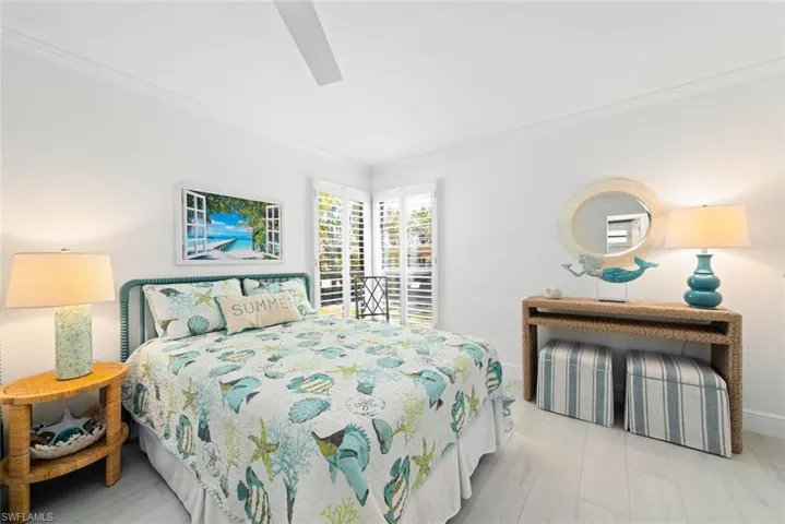 Bedroom featuring baseboards, crown molding, wood finished floors, and a ceiling fan