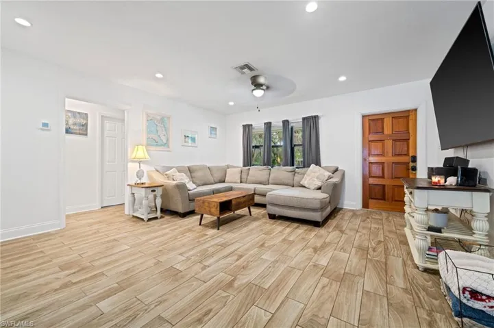 Living room featuring beautiful front door, light wood finished tile floors, recessed lighting, and a ceiling fan
