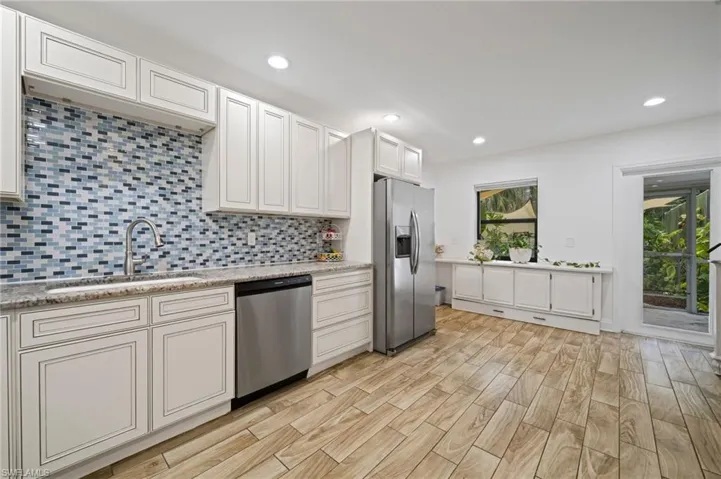 Kitchen featuring stainless steel appliances, decorative backsplash, light wood-style flooring, recessed lighting, and white cream cabinets