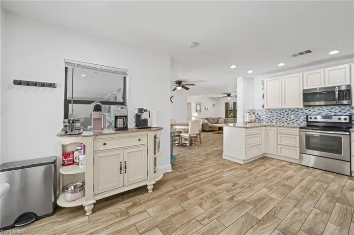 Kitchen featuring stainless steel appliances, open floor plan, light wood-style flooring, backsplash, and recessed lighting