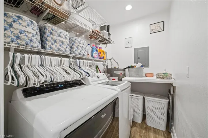 Laundry area featuring washer and clothes dryer, electric panel, wood finished floors, and recessed lighting