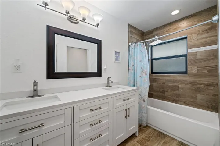 Bathroom #2 with shower / bath combo, double vanity, and wood finished floors