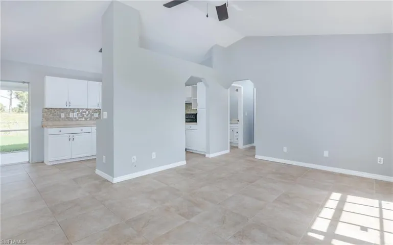 Unfurnished living room featuring high vaulted ceiling, light tile patterned floors, and ceiling fan