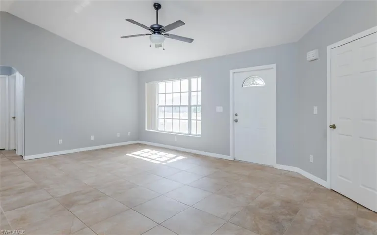 Tiled foyer entrance with ceiling fan and vaulted ceiling