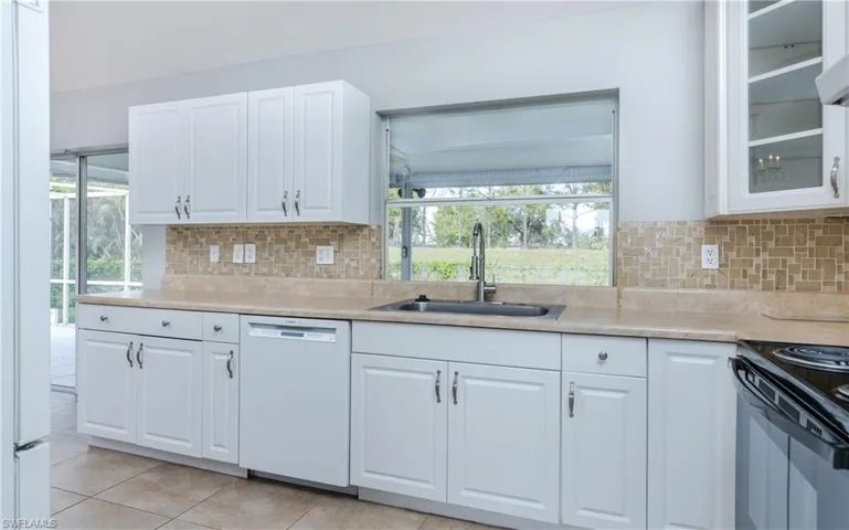 Kitchen with plenty of natural light, white cabinetry, sink, and dishwasher