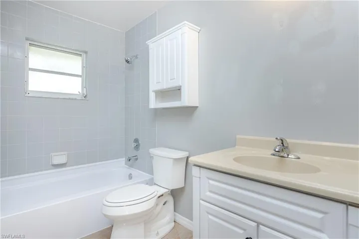 Full bathroom with tile patterned floors, vanity, toilet, and tiled shower / bath