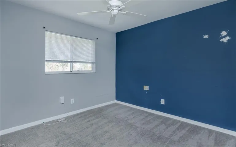 Carpeted empty room featuring ceiling fan