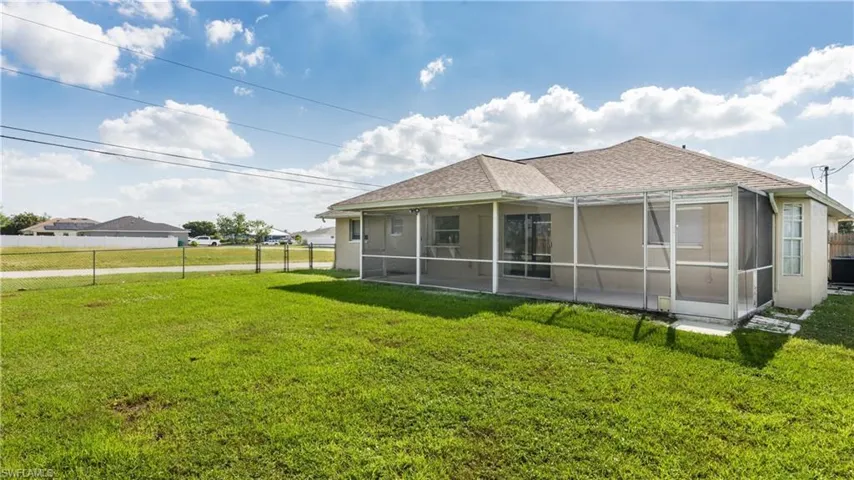 Back of house featuring central air condition unit and a yard