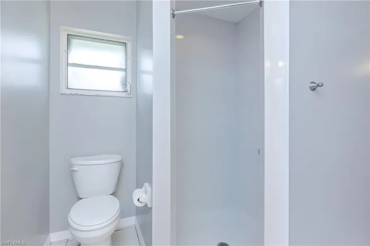 Bathroom with toilet, a shower, and tile patterned floors