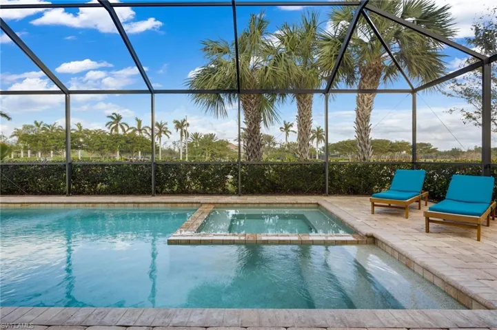 View of swimming pool with an in ground hot tub, a patio area, and a lanai