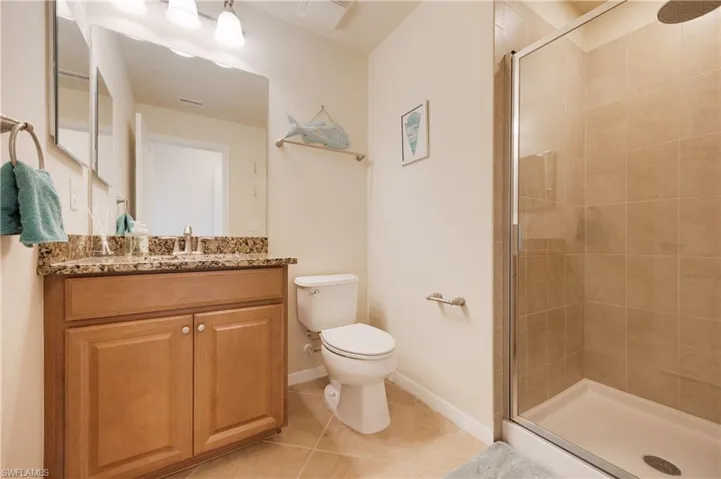 Bathroom with toilet, vanity, tile patterned floors, and a shower with shower door
