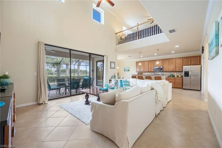 Tiled living room featuring ceiling fan, a towering ceiling, and crown molding